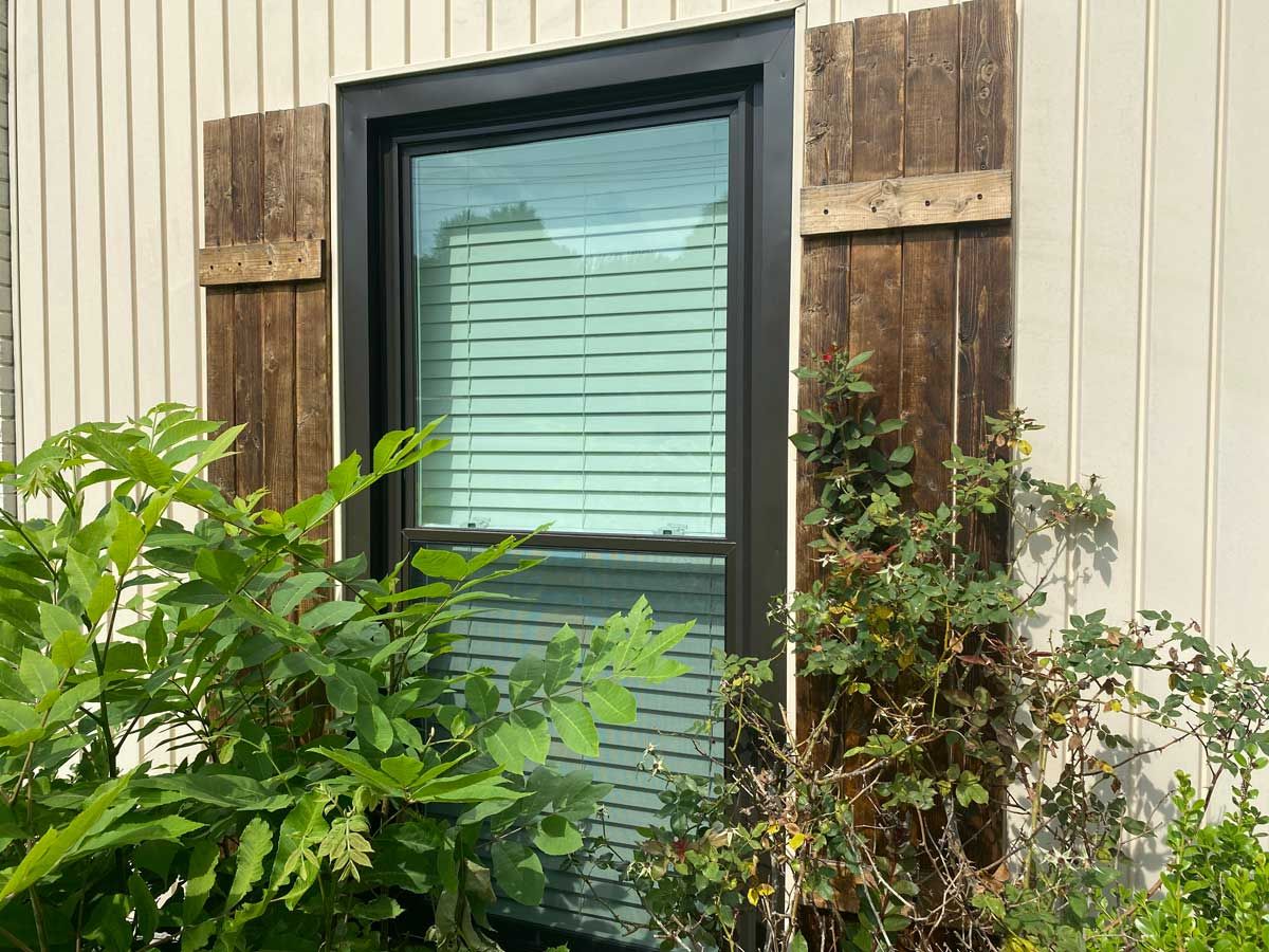 black double hung window installed with shutters